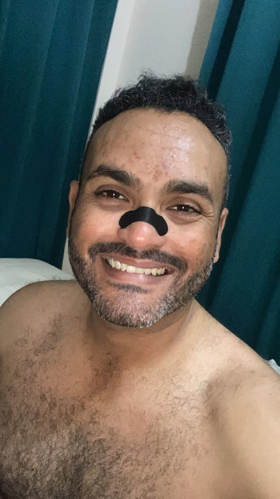 Cliente sonriendo en la cama de noche con la tira nasal negra puesta sobre el puente de la nariz