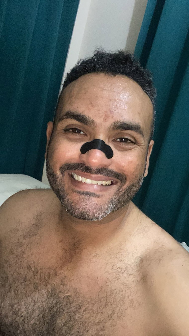 Cliente en la cama de noche con la tira nasal negra puesta, listo para dormir