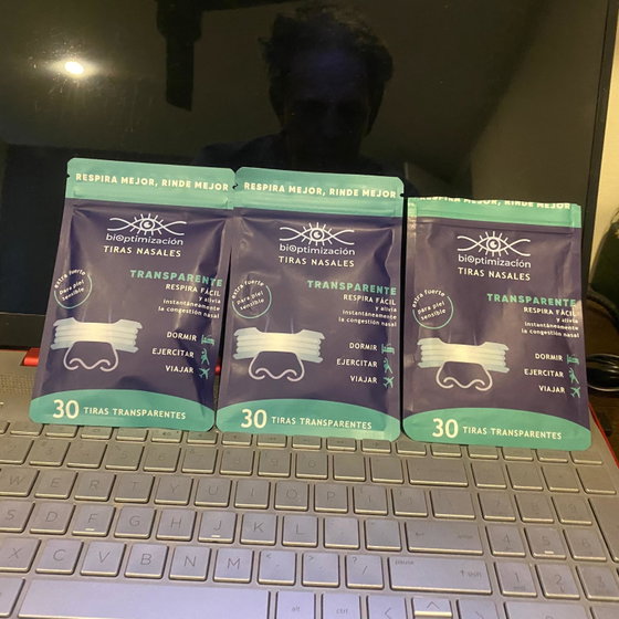 Tres packs de tiras nasales transparentes sobre el teclado de una laptop