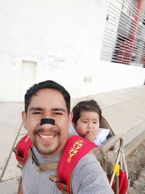 Cliente cargando a su bebé, con la tira nasal negra puesta