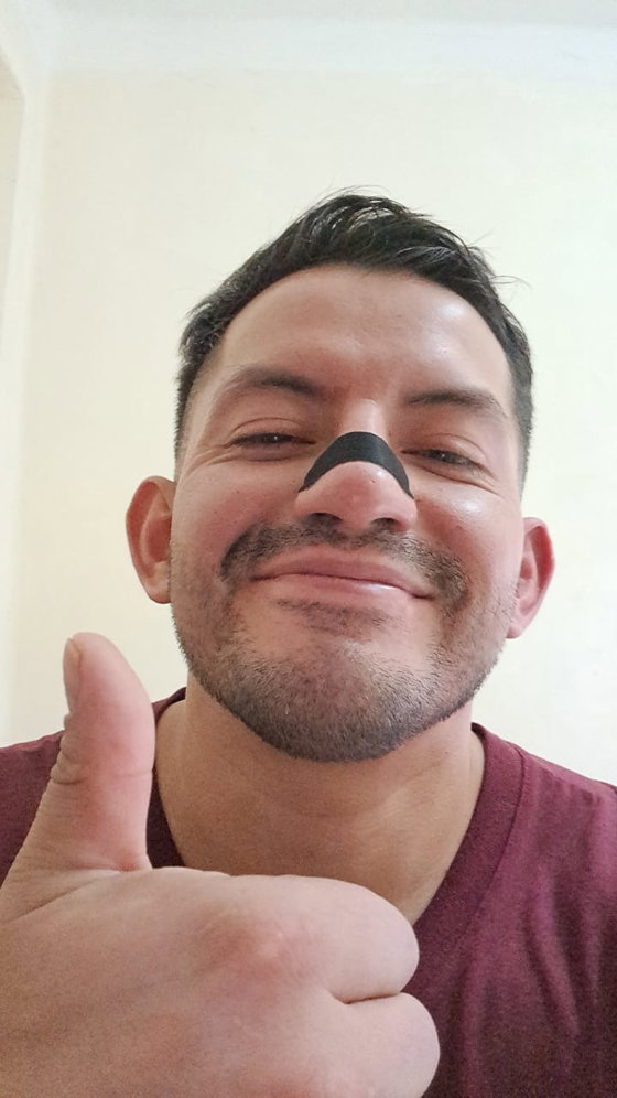 Cliente con la tira nasal negra puesta haciendo el gesto de pulgar arriba