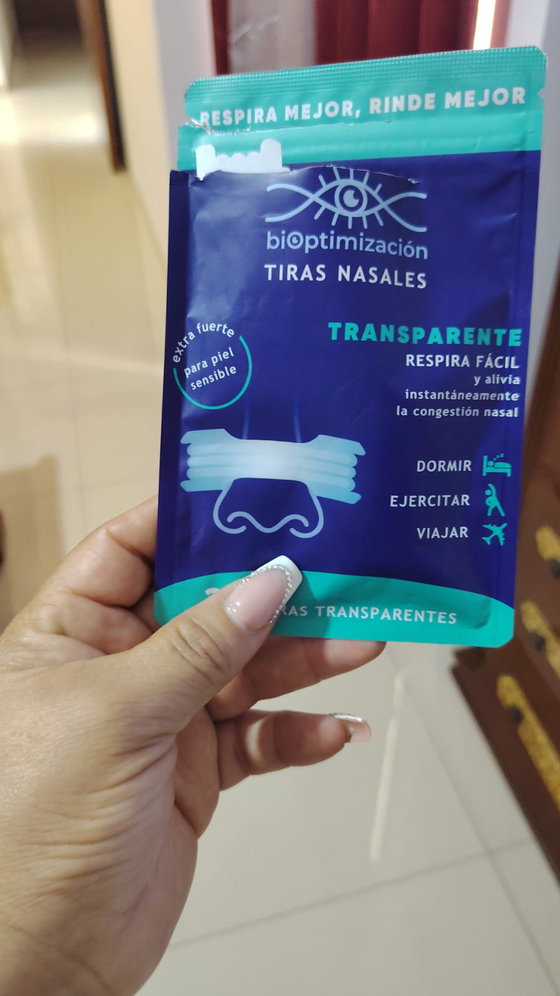 Mano sosteniendo el pack de tiras nasales transparentes sobre fondo neutro