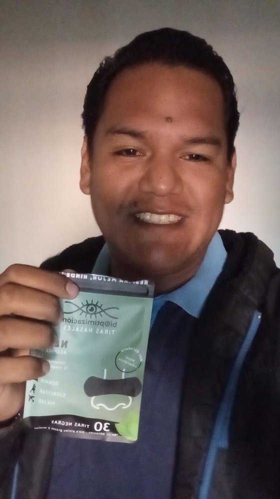 Cliente de traje sonriendo mientras muestra el pack negro de tiras nasales recién recibido